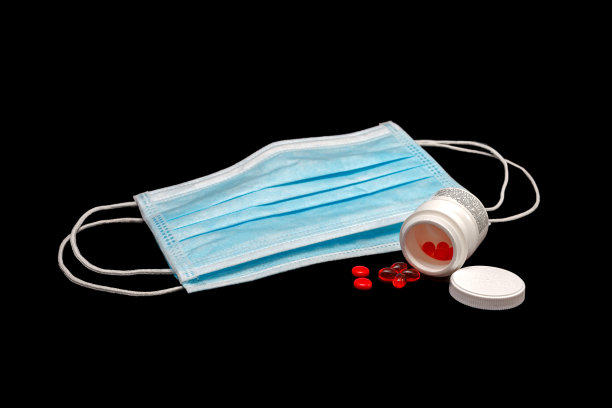 目前在世界各地使用的预防Covid-19传播的个人防护口罩，以及放在黑色背景上的维生素D胶囊和B复合物;影棚拍摄图片下载