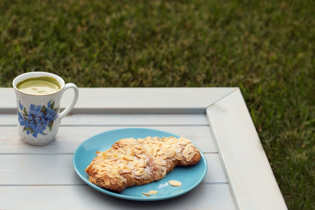 浅蓝色的木桌上放着杏仁羊角面包和抹茶拿铁图片下载
