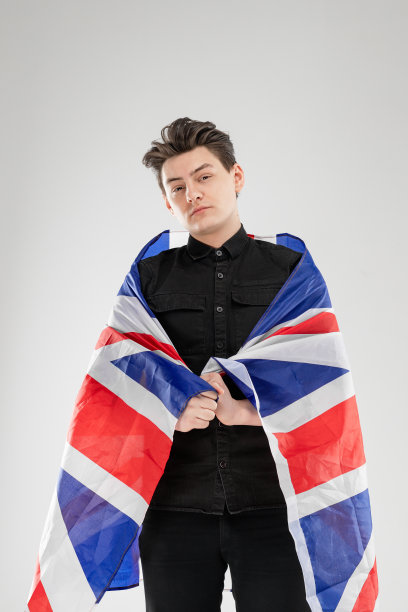 画室里的男人肖像，灰色背景。概念与复制空间。他手里拿着英国国旗图片下载