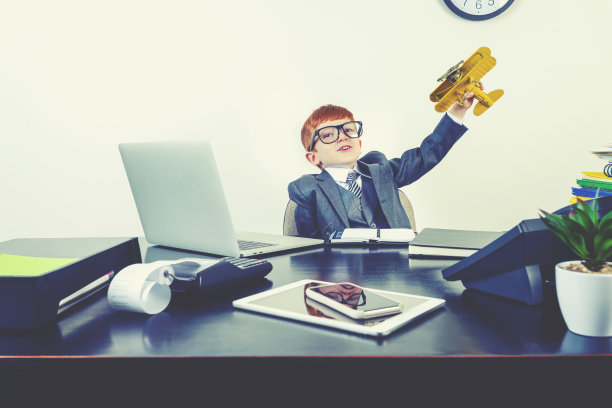 一个穿着西装的小男孩想象自己正在飞机上飞行图片下载