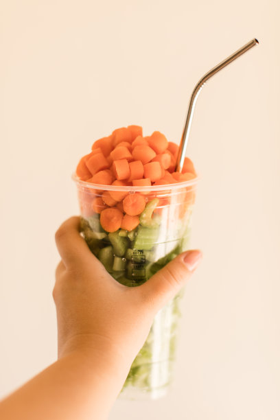 切碎的胡萝卜和芹菜放在冷咖啡杯里，用可重复使用的不锈钢吸管图片下载