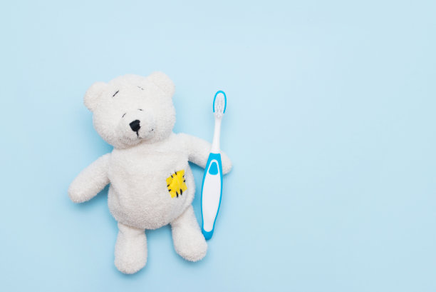白色泰迪熊与牙刷在蓝色背景，复制空间图片下载