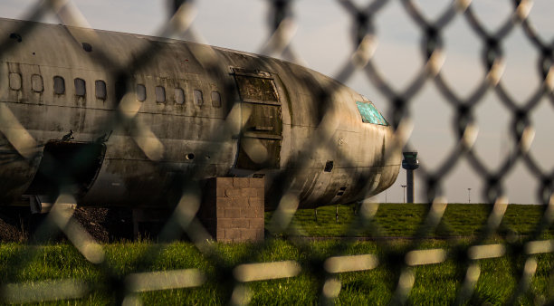 日落时分，废弃的飞机机身在机场中央，背景是控制塔图片下载