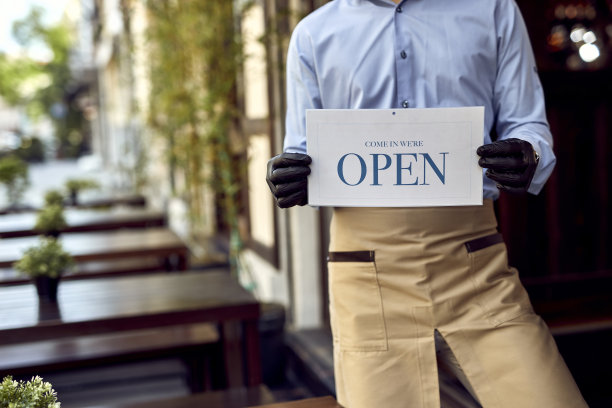酒吧门口举着开门牌子的面目全非的侍者。图片下载