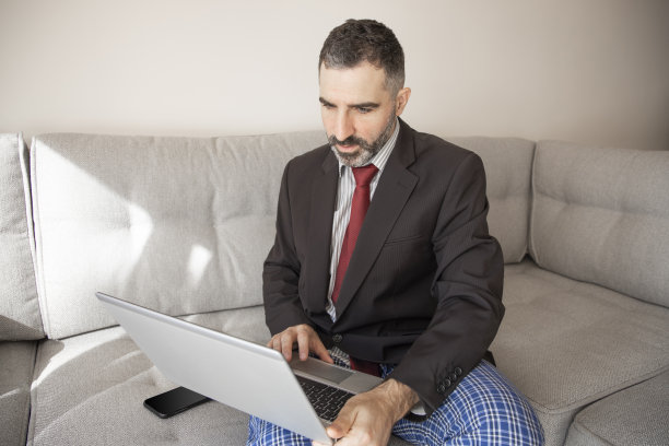 穿着西装和睡裤在家工作喝着咖啡的商人图片下载