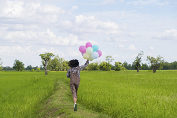 快乐的亚洲小女孩拿着气球在美丽的稻田里奔跑，大自然的背景。图片下载