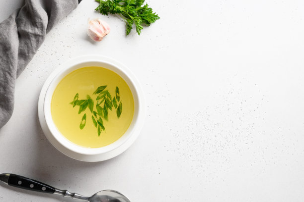 白色的桌子上，白色的碗里盛着葱鸡汤。副本的空间。前视图。图片下载