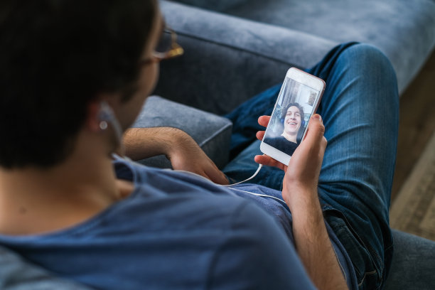 一个男性的手在视频通话期间持有智能手机的近距离图片下载