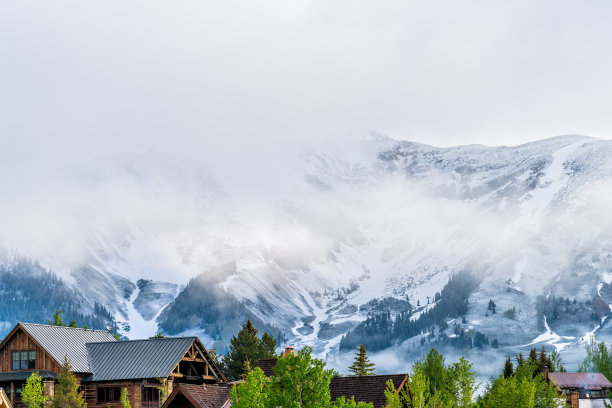 Mount Crested Butte，美国科罗拉多州的村庄在夏天与云彩和雾霭日出早上和房子在山上与绿色的树木图片下载