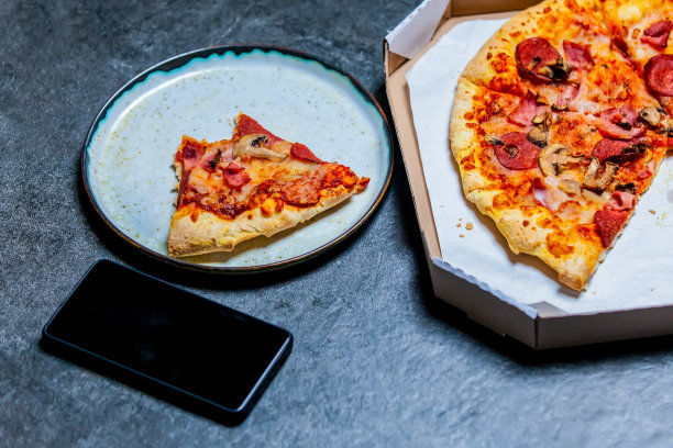 地中海披萨，装在盒子里，桌上放着手机图片下载