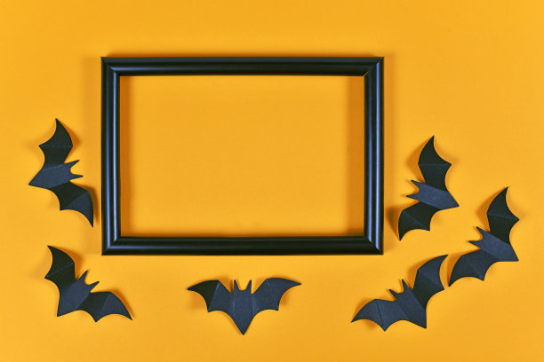 节日的万圣节平躺着黑色的飞行纸工艺蝙蝠周围空的图片框在橙色的背景图片下载