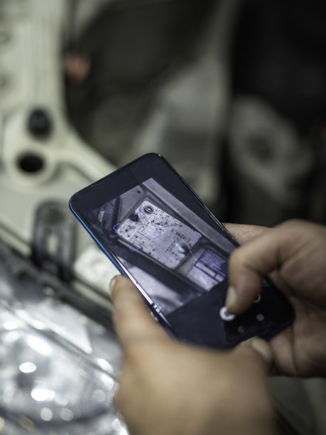 汽车修理工正在检查汽车的发动机。技术员用手机检查。图片下载