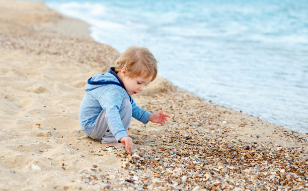 漂亮的小男孩在玩沙子。假期、暑假图片下载