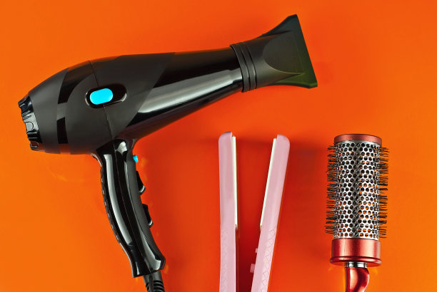 电吹风和梳子孤立在一个橙色的背景。图片下载