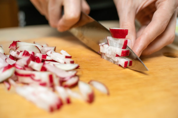 女人的手在木板上用刀切萝卜图片下载