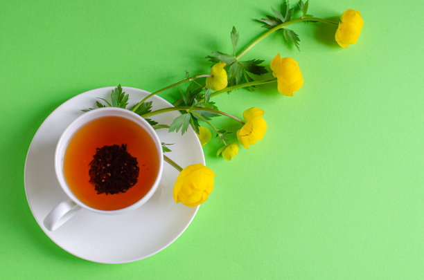 一杯红茶，几块巧克力，绿色背景上盛开着欧洲巨人的黄花。巧克力日和早茶。图片下载