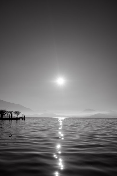 湖面或海面上的太阳。阳光照在水面上，像月光照耀下的小路。黑白照片。图片下载