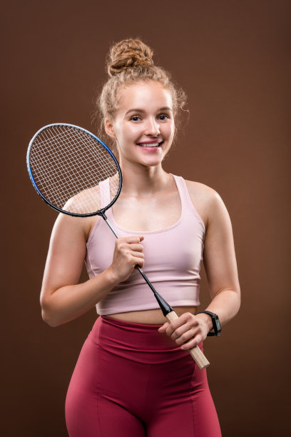 穿着运动服的漂亮女孩拿着网球拍微笑着看着你图片下载