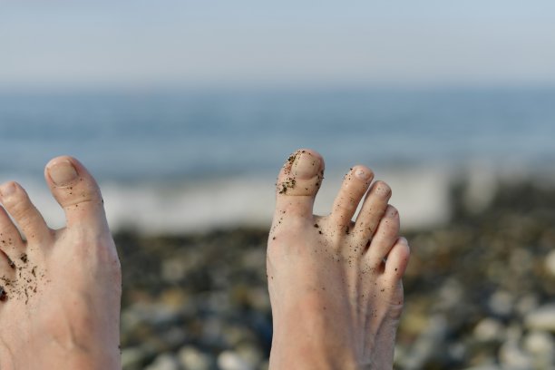 两只赤裸的脚对着大海是模糊的。图片下载