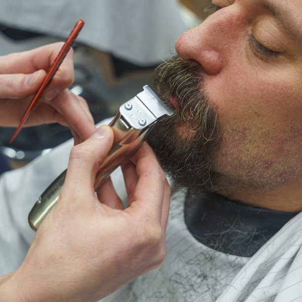 理发师在理发店里用剃须机修剪胡子。弄头发的过程。发型的概念。图片下载
