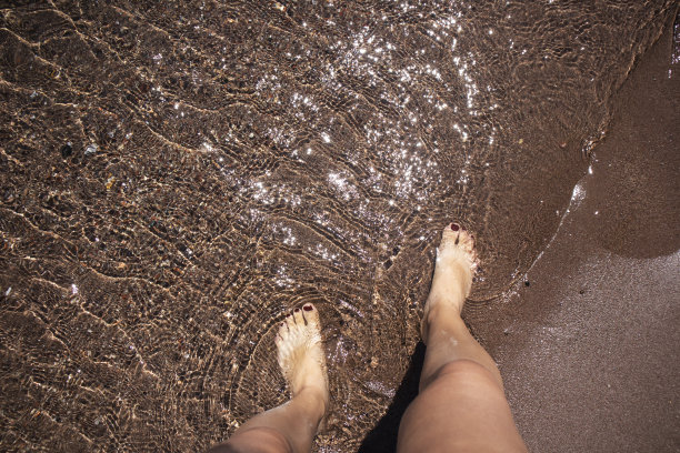 脚踩在海沙上。海边度假，暑假图片下载