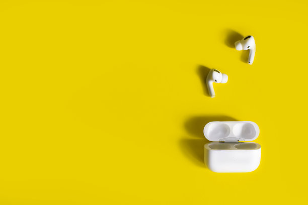 黄色背景的白色无线耳机。带耳硅胶塞。图片下载