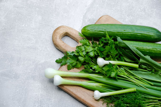 新鲜蔬菜放在木砧板上。俯视图黄瓜，欧芹和绿洋葱。从上面看沙拉配料。节食食物，素食菜单概念。图片下载