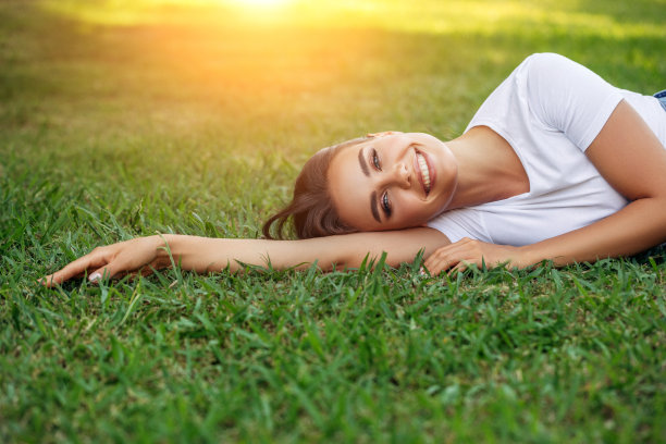 微笑的年轻女子躺在草地上图片下载