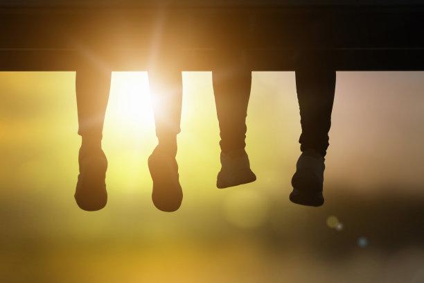 女人放松坐脚荡秋千在一个豪华的海滨酒店度假村在日落享受完美的海滩度假。自然背景模糊温暖的颜色和明亮的阳光。图片下载