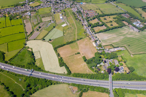 这是一架无人机拍摄的英国西约克郡布拉德福德郡克莱希顿村的照片，照片显示了一个阳光明媚的夏日，M63高速公路旁的农田图片下载