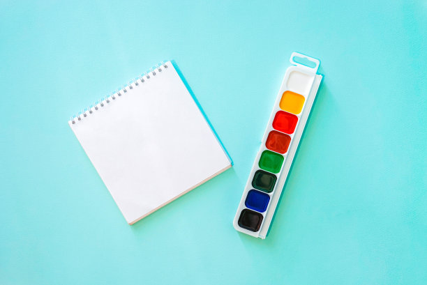 水平的极简特写平铺构图与清晰的纸笔记和彩色水彩油漆在浅蓝色的背景。照片中央的物体。文具。水平的照片。回归学校、大学、教育理念。的空间图片下载