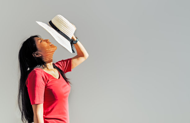 深色头发的拉丁妇女在侧面拿一顶帽子在她的脸前，一只手保护自己免受太阳图片下载