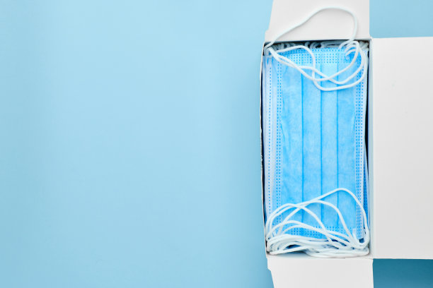 新的蓝色外科防护口罩，在有拷贝空间的蓝色背景的盒子里。给医院运送医疗用品图片下载
