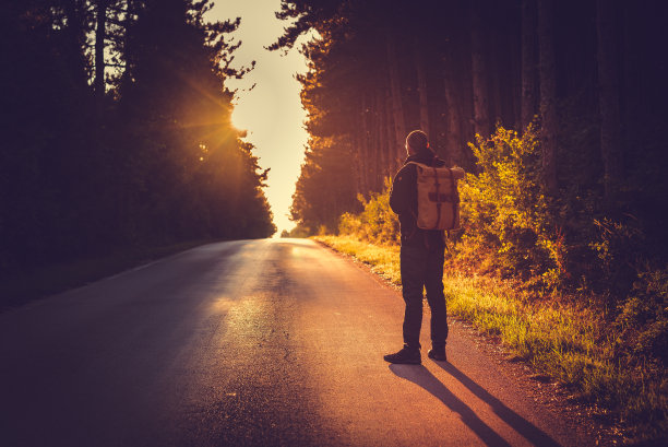 一个背着背包的男人站在路上图片下载