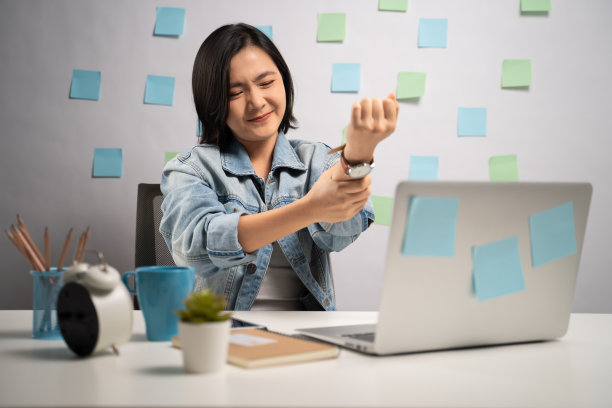 一名亚洲女性坐在家里的办公室里用笔记本电脑工作，身体疼痛。亲密。居家办公预防COVID-19概念。图片下载