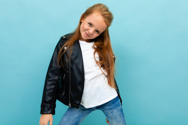 迷人的女孩在一个休闲的外观与皮夹克和牛仔裤解开她的夹克在浅蓝色的墙壁图片下载