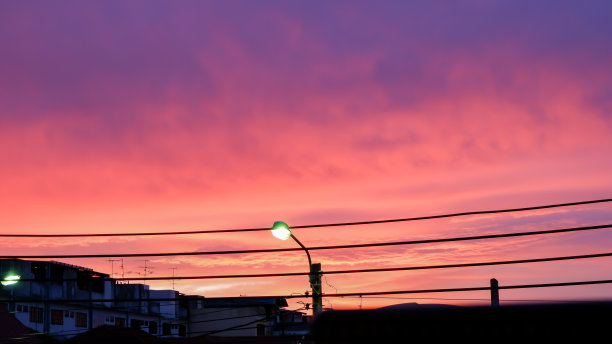 街灯和云的剪影照亮背景金色的夕阳在傍晚的天空。图片下载
