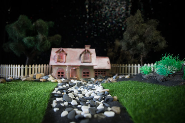 傍晚，在长满青草和雏菊的草地上，有一座模型屋。图片下载