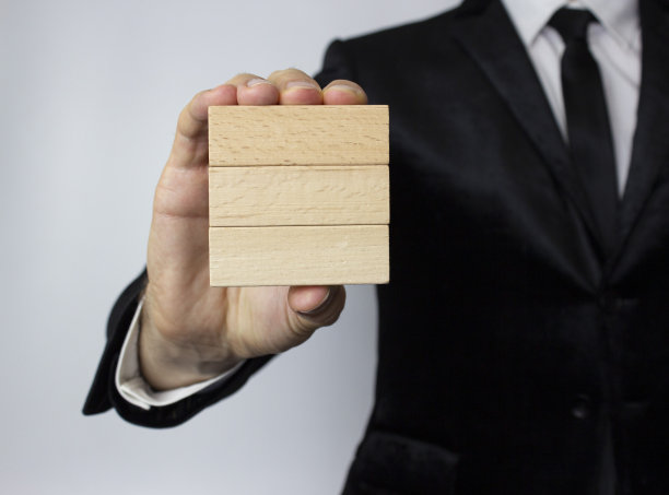 一个穿着夹克、白衬衫、打着领带的年轻商人手里拿着三个木块。图片下载