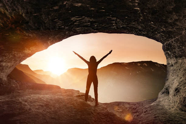 一个女人的剪影在山洞里迎接日出图片下载