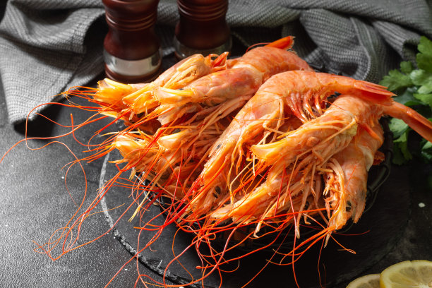 黑色的餐桌上放着一只黑色的金属篮子，里面装着几只大螯虾。大量的小龙虾图片下载