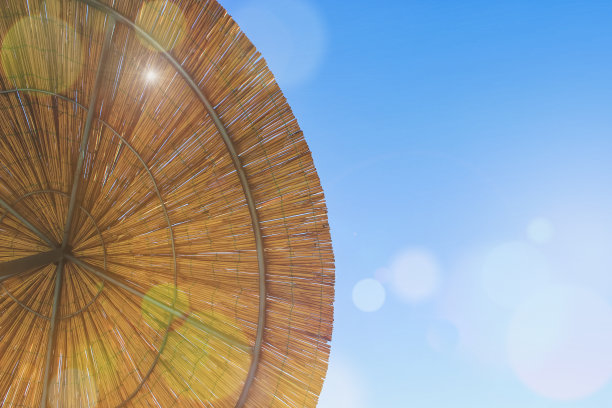 阳光透过竹伞照进来。茅草屋顶背景，干草或干草背景。稻草海滩遮阳视图从上面图片下载