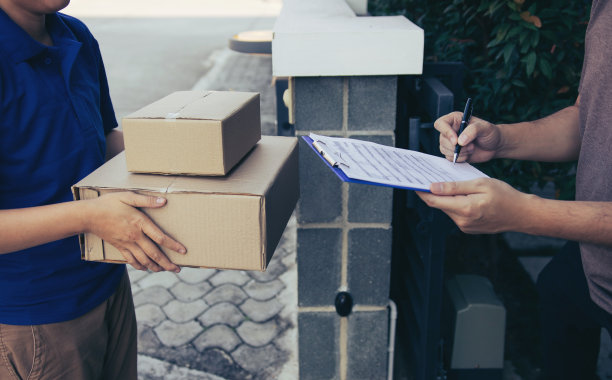 快递青年站在家门口，拿着包裹等待青年男子签收。图片下载