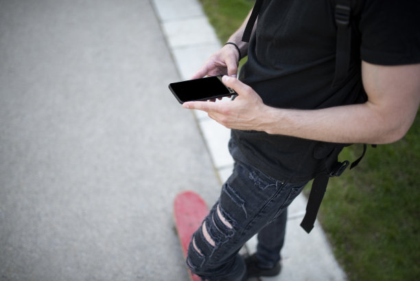 现代学生在黑色的城市行走和去学校的智能手机库存照片图片下载