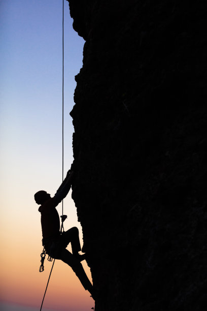 登山者从岩石表面上升到日落股票照片图片下载