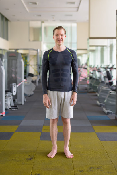 2019冠状病毒病期间，一名年轻帅气男子在健身房微笑的全身照片图片下载