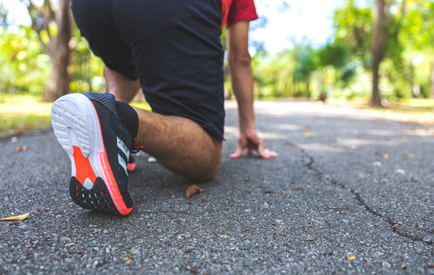 在公园的道路上跑步的运动员，以柔和的焦点和过光为背景图片下载