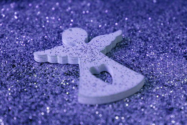 一个白色小天使的木制小雕像在灿烂的背景上。圣诞节的概念。图片下载