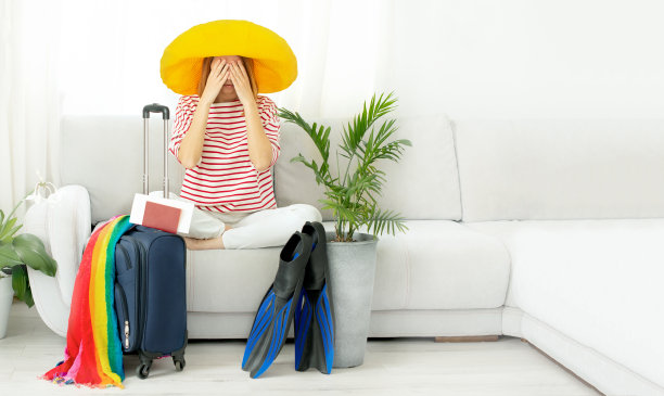 戴着黄色帽子的美丽心烦意乱的女孩呆在家里，计划去度假。等待旅行。由于隔离和COVID-19，关闭边境和禁止航班图片下载