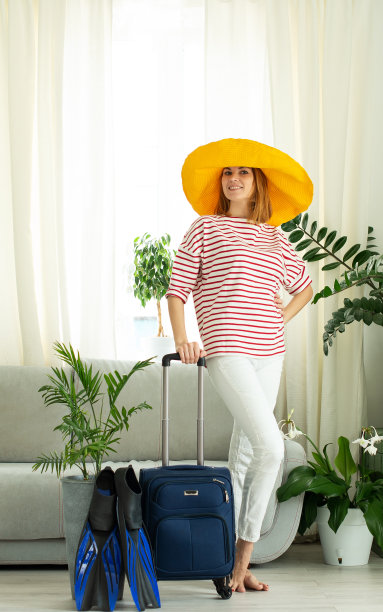 一个戴着黄色帽子的漂亮女孩呆在家里，计划去度假。潜水用的手提箱和脚蹼。等待旅行。由于隔离和COVID-19，关闭边境和禁止航班图片下载